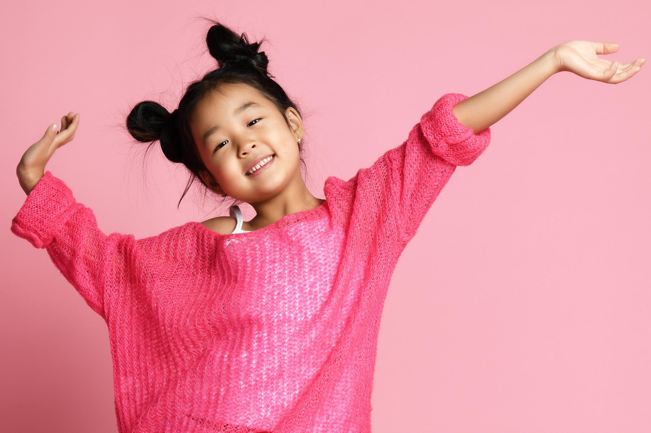 Young girl in bright pink sweater with joyful pose